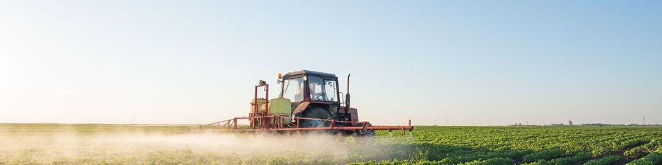 Trattore in campo al tramonto: Mezzo agricolo in attività tra filari, illuminato dalla luce calda del tramonto.