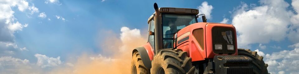 Trattore che ara un terreno: Veicolo agricolo in primo piano mentre prepara il suolo per la prossima semina.