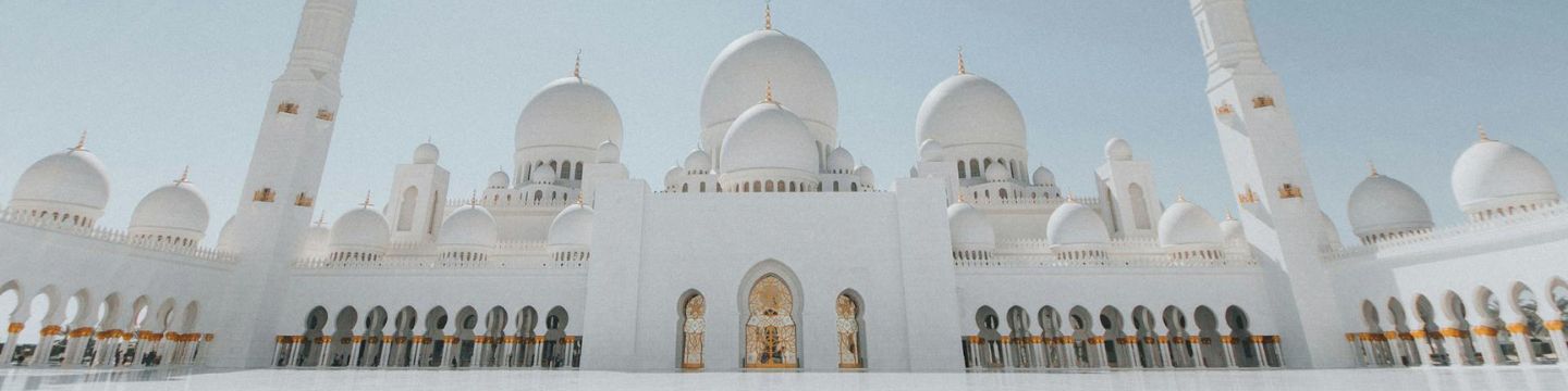 Struttura monumentale bianca con decorazioni arabe, simbolo culturale dell'Arabia Saudita sotto il sole brillante.