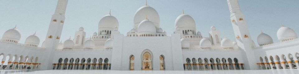 Struttura monumentale bianca con decorazioni arabe, simbolo culturale dell'Arabia Saudita sotto il sole brillante.