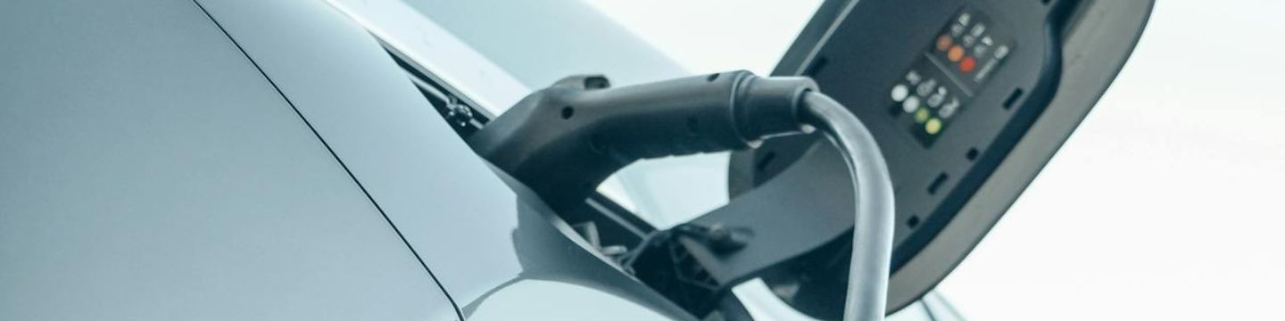 Veicolo elettrico in ricarica presso una colonnina moderna, simbolo di mobilità sostenibile e tecnologie pulite.