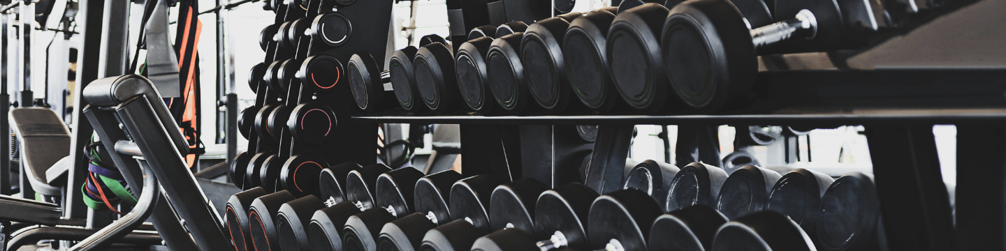 Dettaglio di mani su bilanciere: Mani che stringono un bilanciere durante un sollevamento, in un ambiente di palestra.