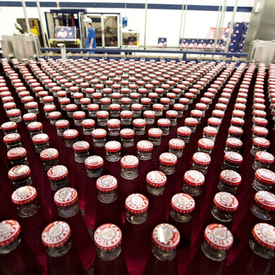 Una serie di bottigliette Campari ordinate con precisione, simbolo della cura artigianale e dell’inconfondibile rosso del brand.