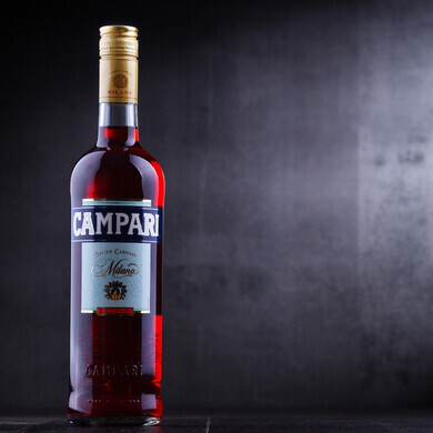 Primo piano di una bottiglia Campari, emblema dello stile e della storia del celebre aperitivo milanese.