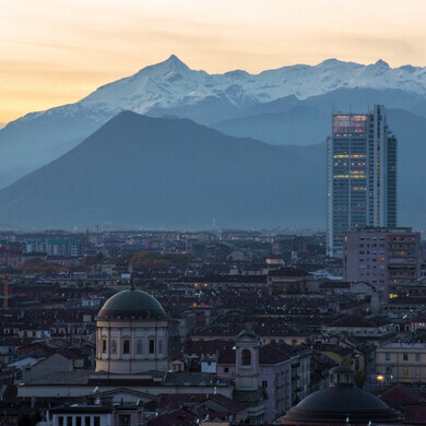 Vista dall’alto di Torino con la cupola della Chiesa di San Massimo, il grattacielo Grattacielo Intesa Sanpaolo e le Alpi innevate sullo sfondo.