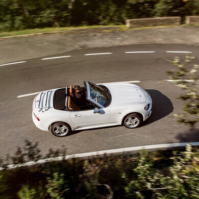 Fiat 124 Spider cabriolet, veicolo sportivo elegante, ritratta in strada panoramica.