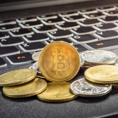 Monete Bitcoin poggiate su un laptop Monete Bitcoin sovrapposte poggiate su un laptop