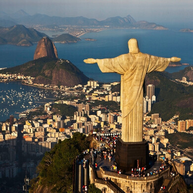 Veduta del Cristo Redentore che si erge maestoso sulla cima del Corcovado, con la città di Rio de Janeiro e le montagne circostanti visibili sullo sfondo.