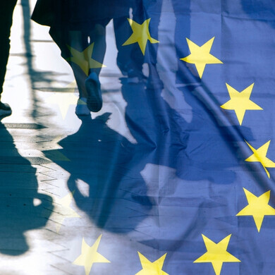 Bandiera dell’Unione europea con ombre di persone, immagine concettuale a tema politico.