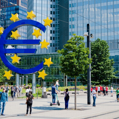 Grande scultura del simbolo dell’Euro davanti alla Banca Centrale Europea a Francoforte, Germania, con persone visibili.