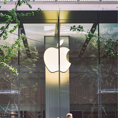Logo Apple bianco e illuminato all’interno di uno spazio architettonico