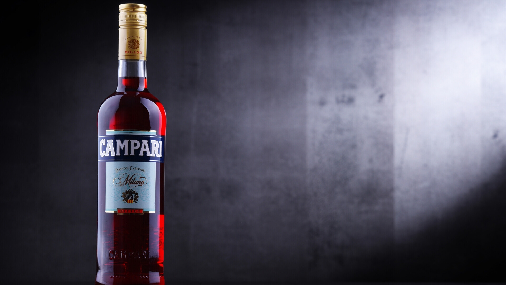 Primo piano di una bottiglia Campari, emblema dello stile e della storia del celebre aperitivo milanese.