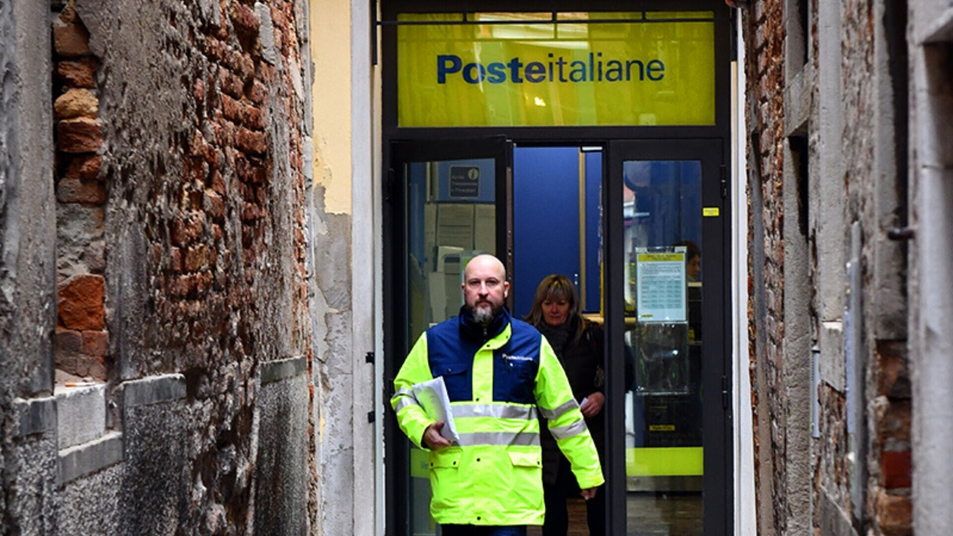 Poste italiane, ingresso ufficio postale Ingresso di un ufficio postale Poste Italiane, con logo giallo-blu e persone in entrata e uscita
