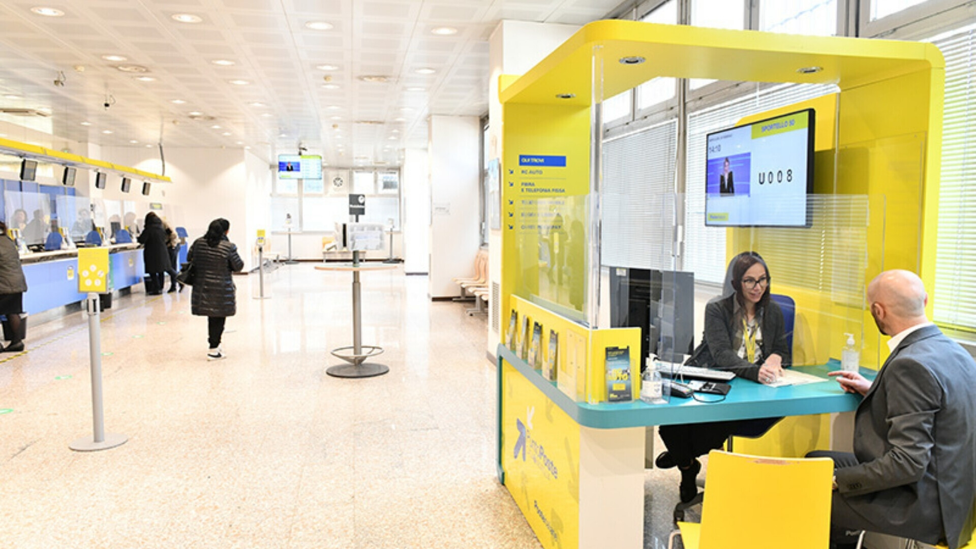 Interno di un ufficio postale Poste Italiane con sportelli aperti al pubblico e personale al servizio dei clienti.
