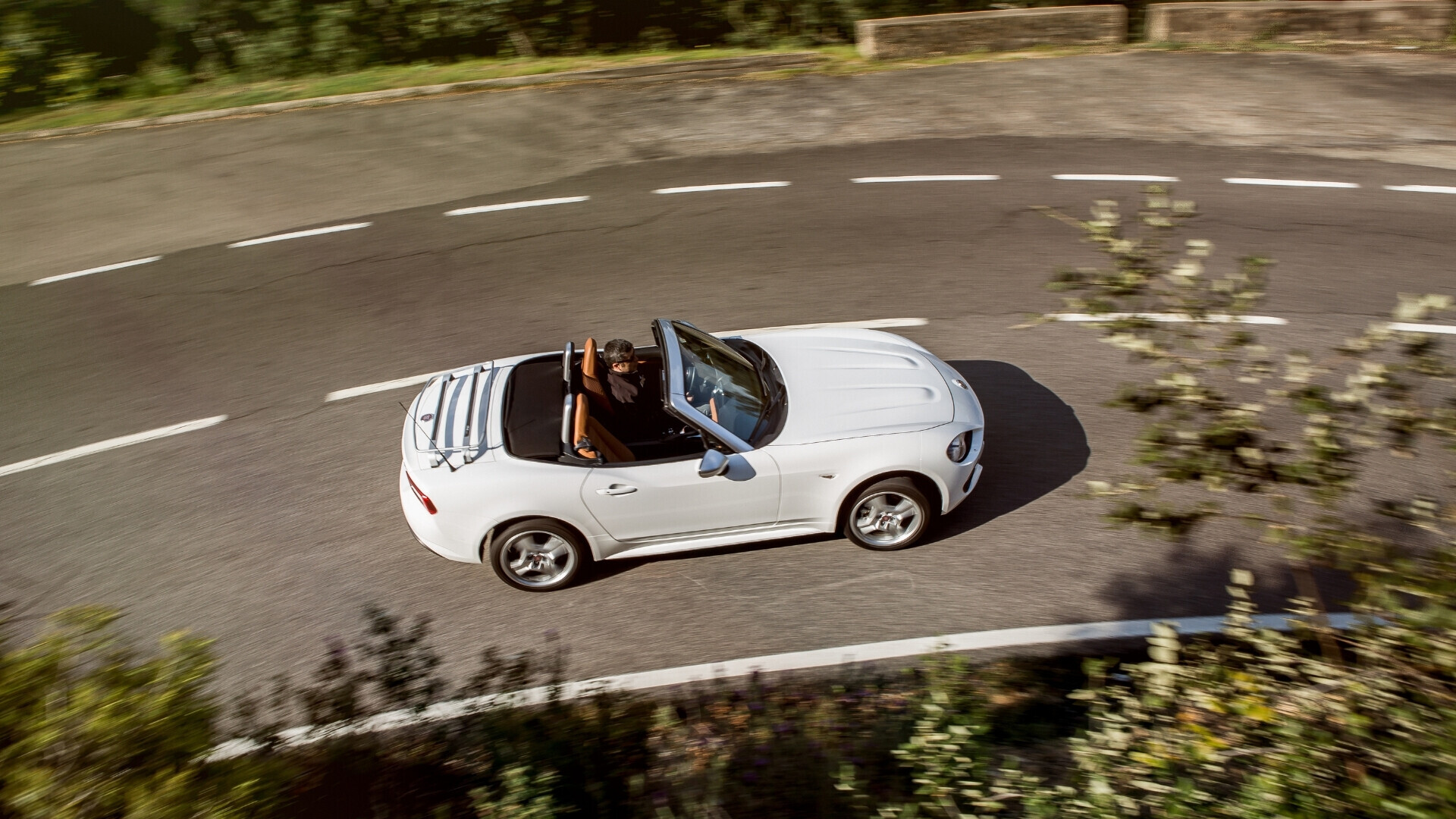 Fiat 124 Spider cabriolet, veicolo sportivo elegante, ritratta in strada panoramica.