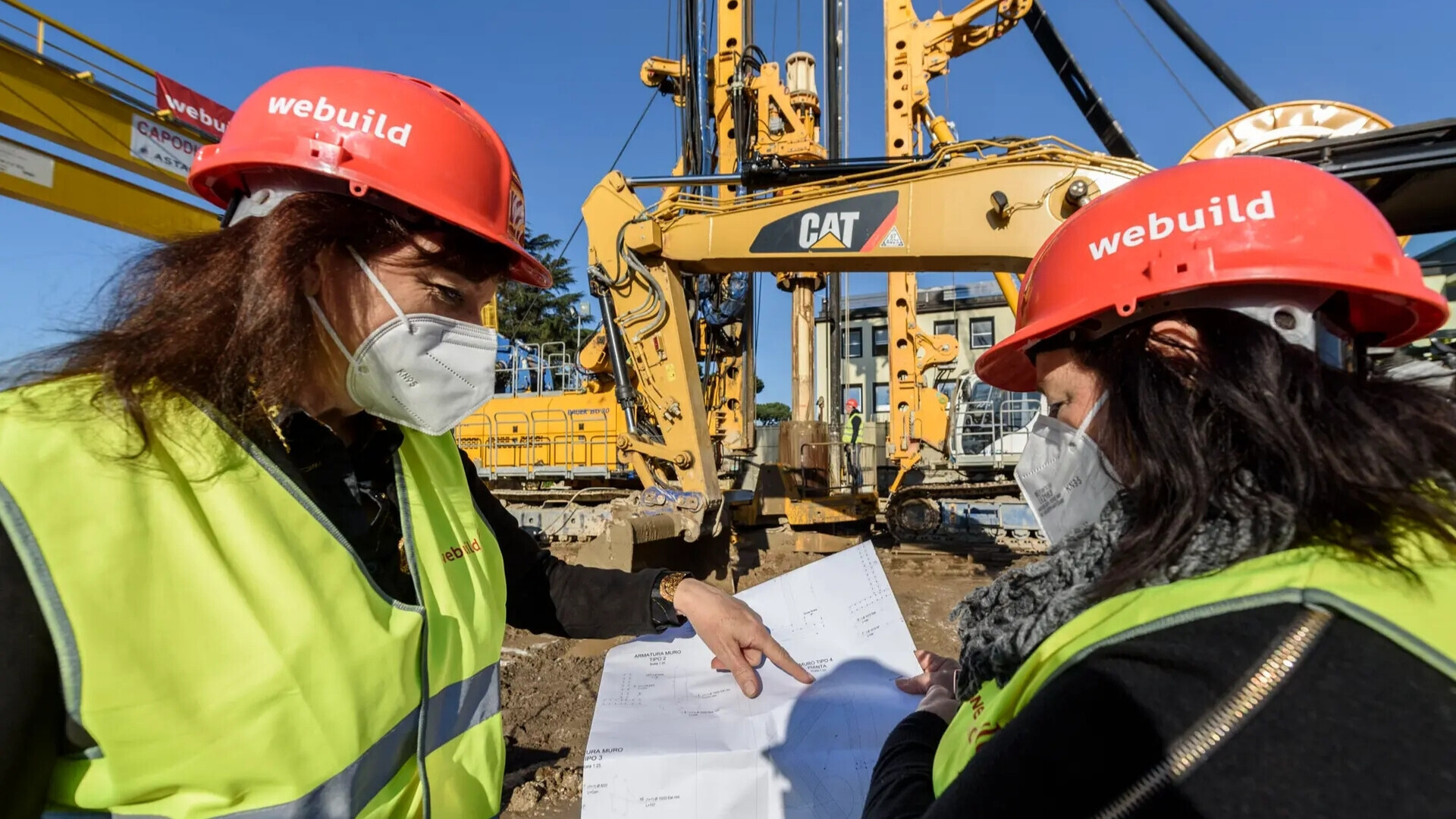 Team di dipendenti Webuild al lavoro in cantiere, con caschi e dispositivi di sicurezza visibili.