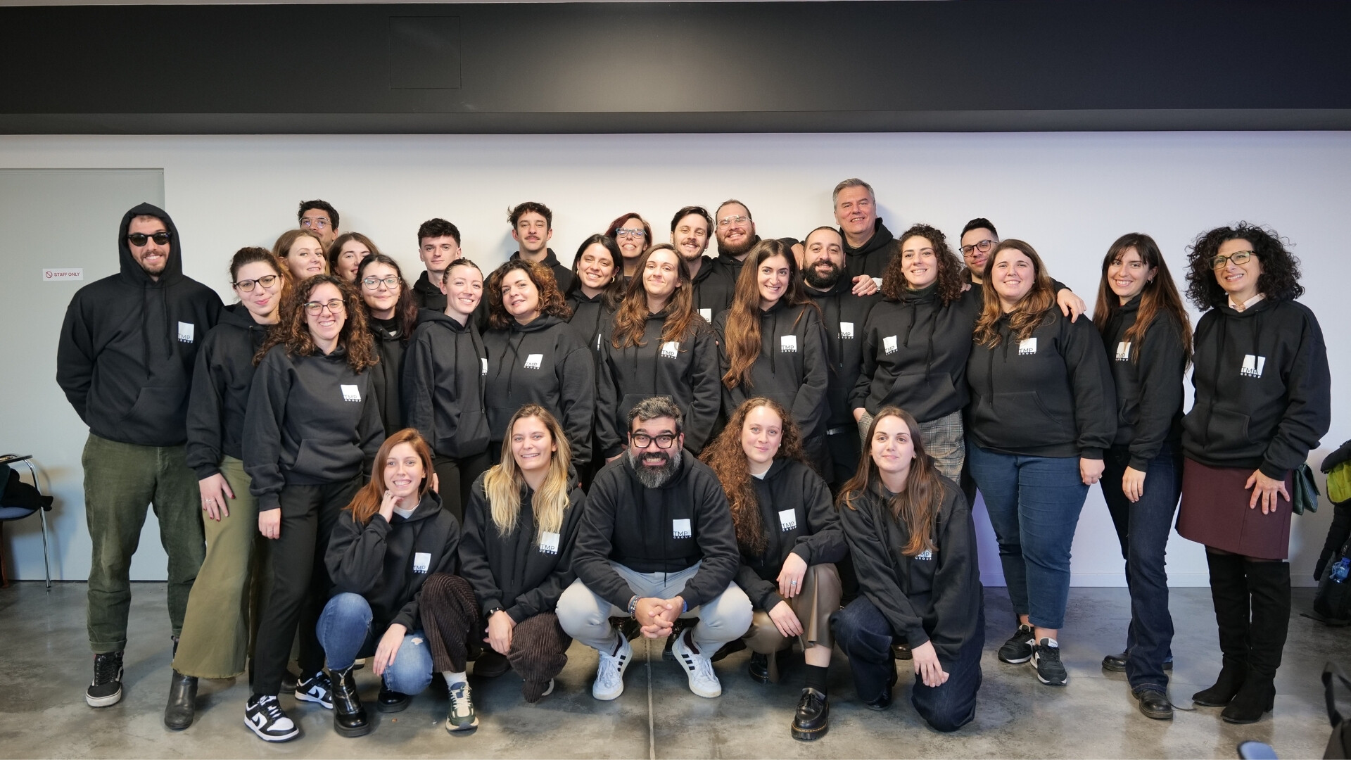 Foto di gruppo completa del TMP Group, che mostra tutti i collaboratori insieme in un ambiente lavorativo.