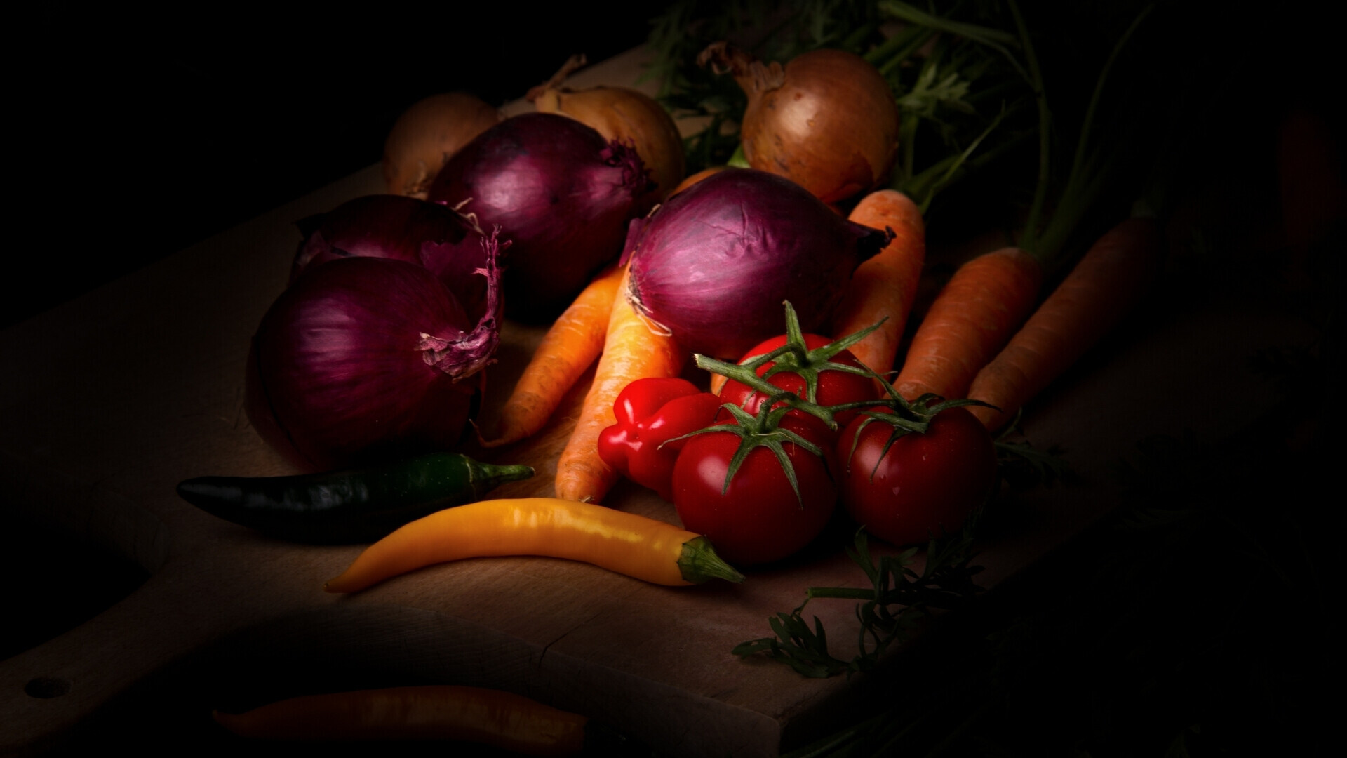 Frutta e verdura disposte su legno con illuminazione soffusa