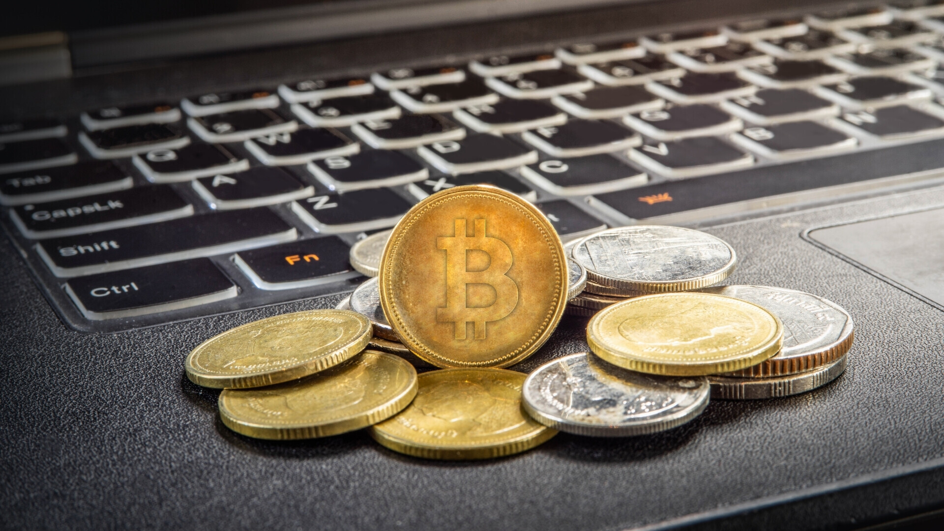 Monete Bitcoin poggiate su un laptop Monete Bitcoin sovrapposte poggiate su un laptop