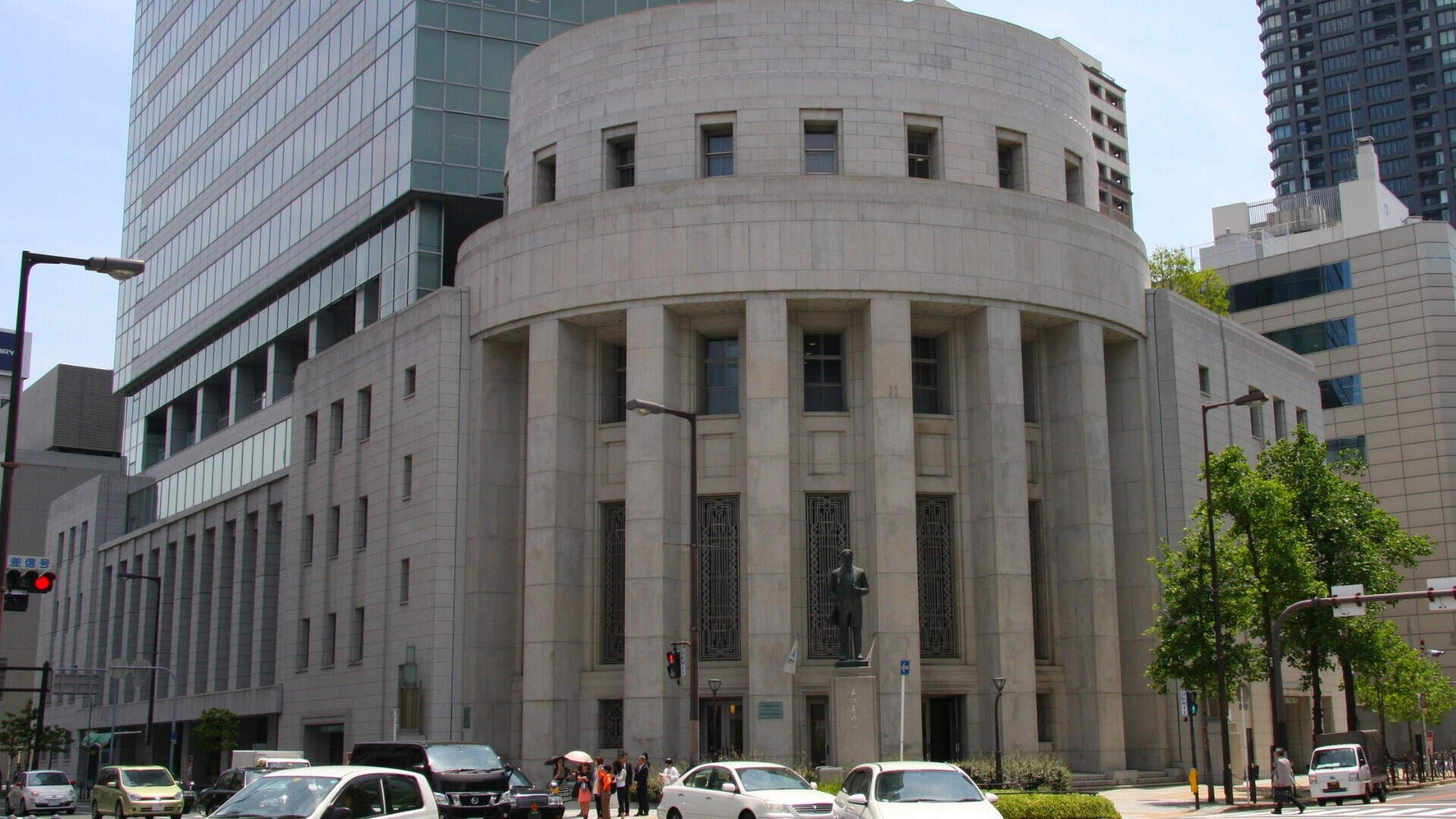 Grattacielo moderno che ospita la Borsa di Osaka, con facciata in vetro e cielo urbano sullo sfondo.