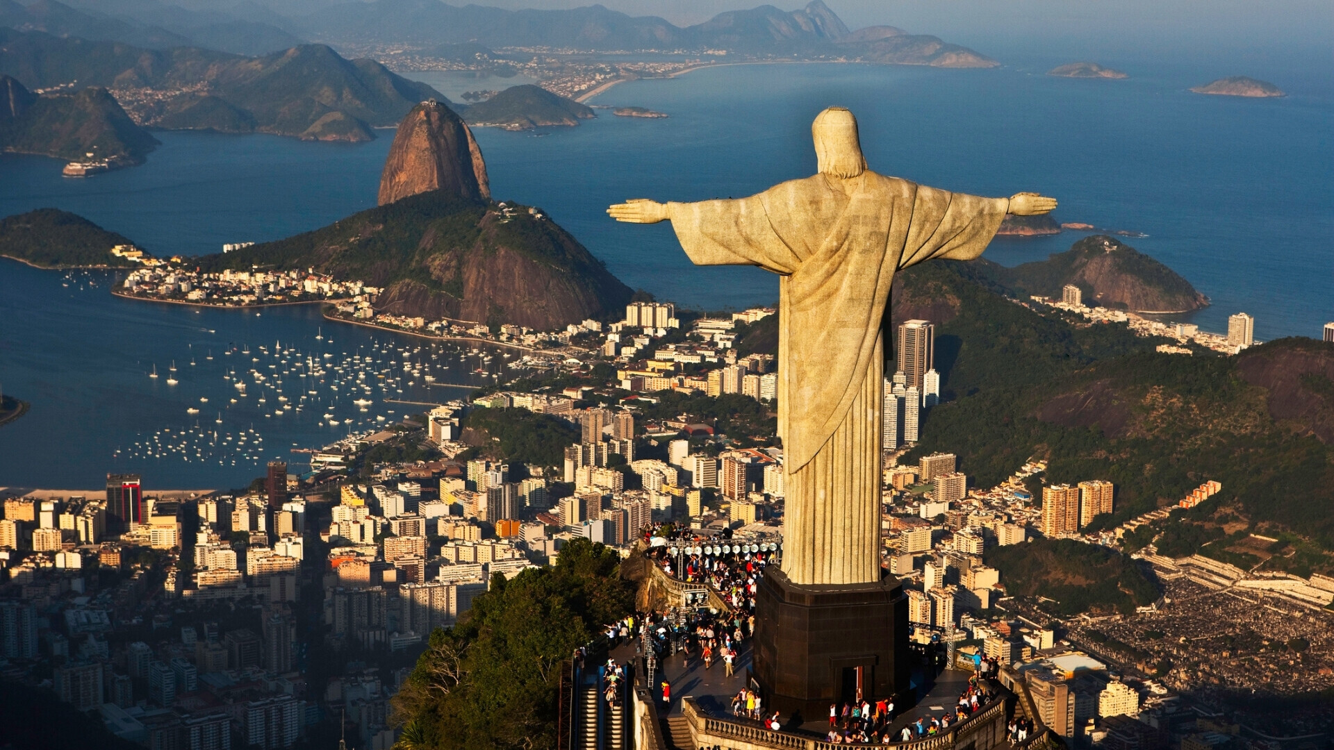 Veduta del Cristo Redentore che si erge maestoso sulla cima del Corcovado, con la città di Rio de Janeiro e le montagne circostanti visibili sullo sfondo.
