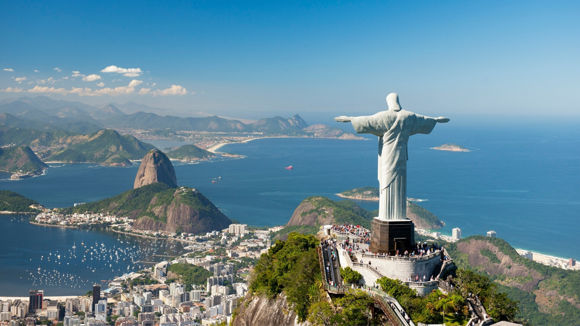 Veduta aerea della statua del Cristo Redentore con la montagna del Pan di Zucchero, la spiaggia di Copacabana e la spiaggia di Botafogo sullo sfondo.