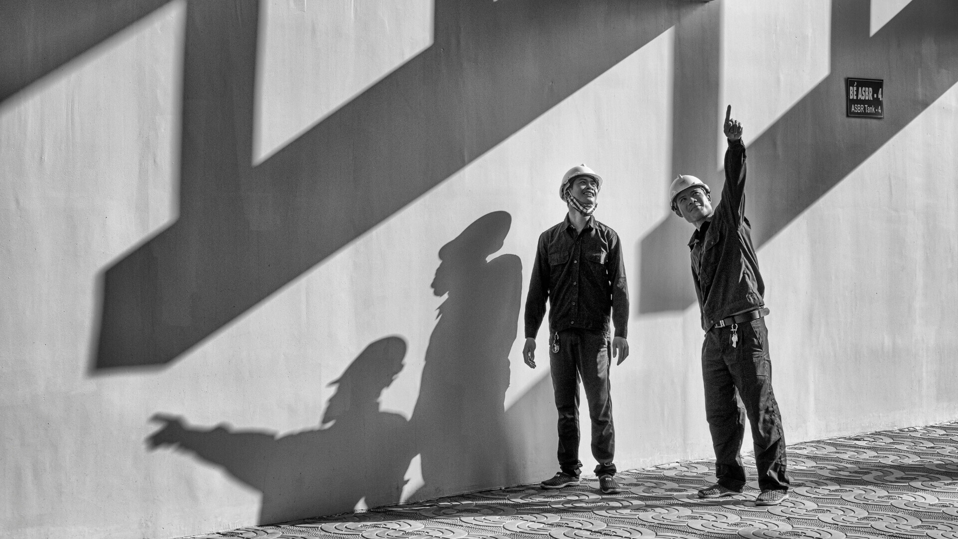 Operai con caschi e giubbotti di sicurezza intenti a lavorare in un cantiere edile attivo.