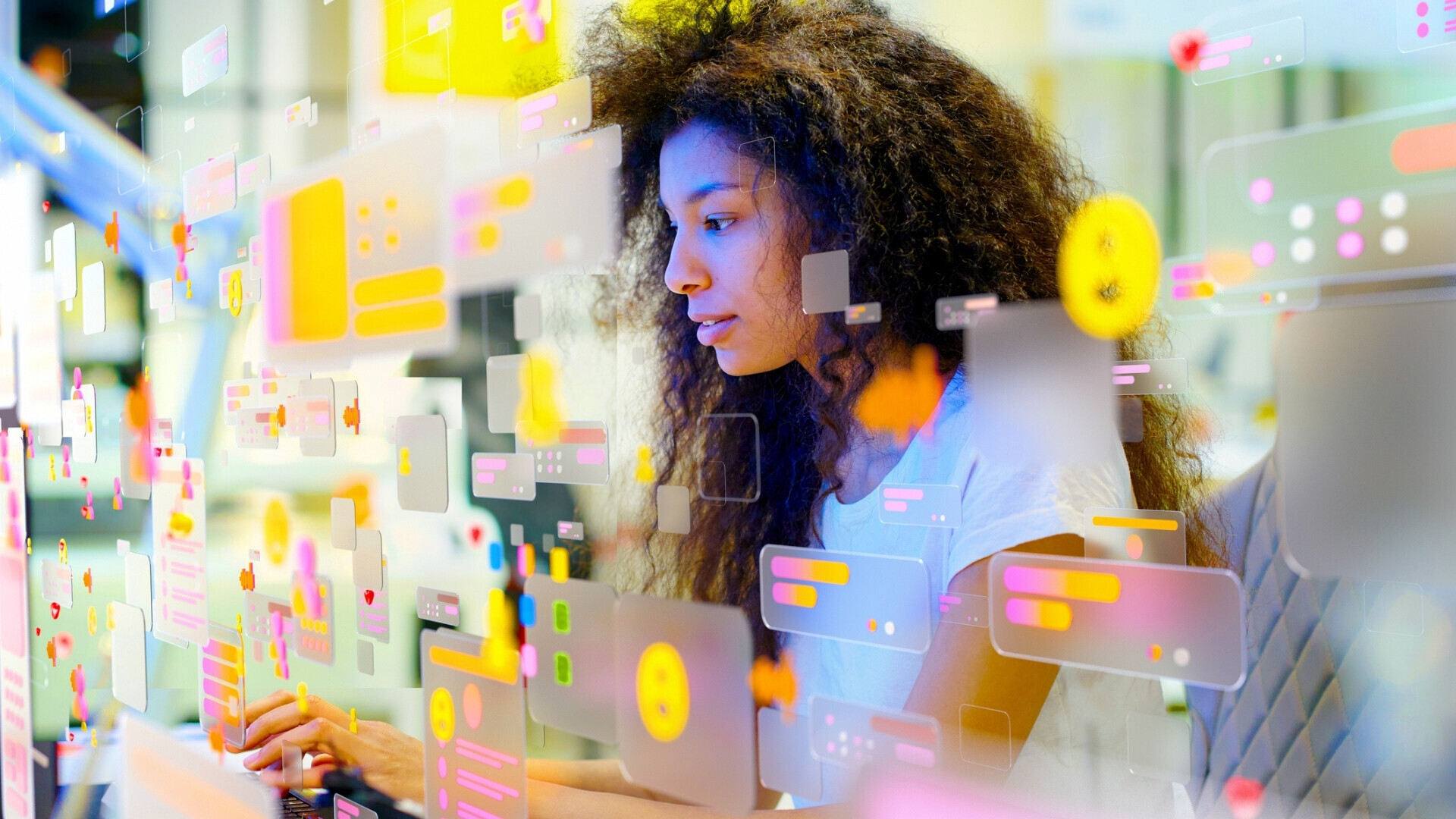 Ritratto di una giovane donna che lavora in un ufficio moderno, circondata da icone multicolori dei social media e schermi di dati. Concetto di personalizzazione dei dati e social media.