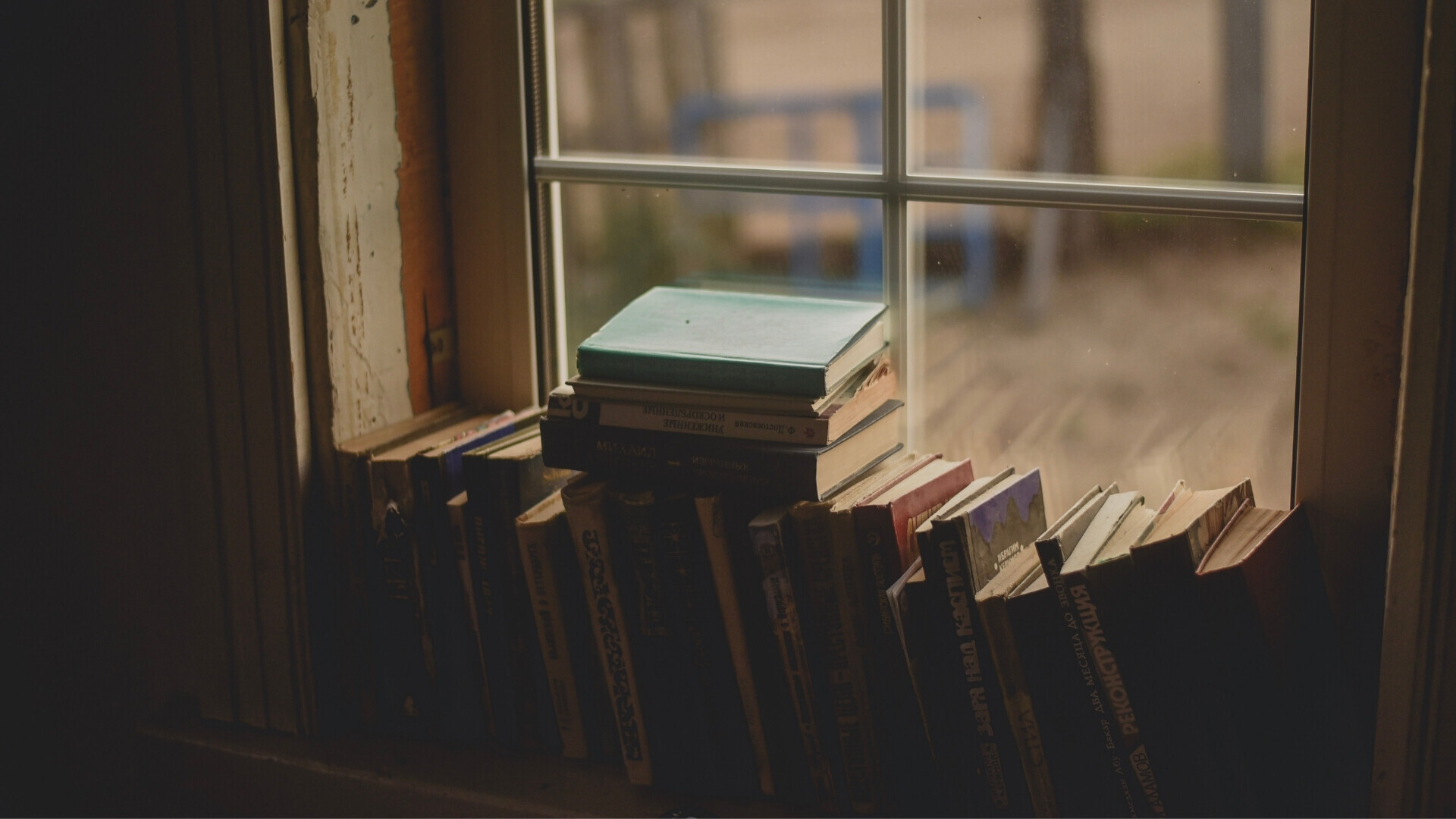 Libri antichi sul davanzale di una finestra Libri antichi disposti su un davanzale di legno, con luce naturale che illumina le copertine