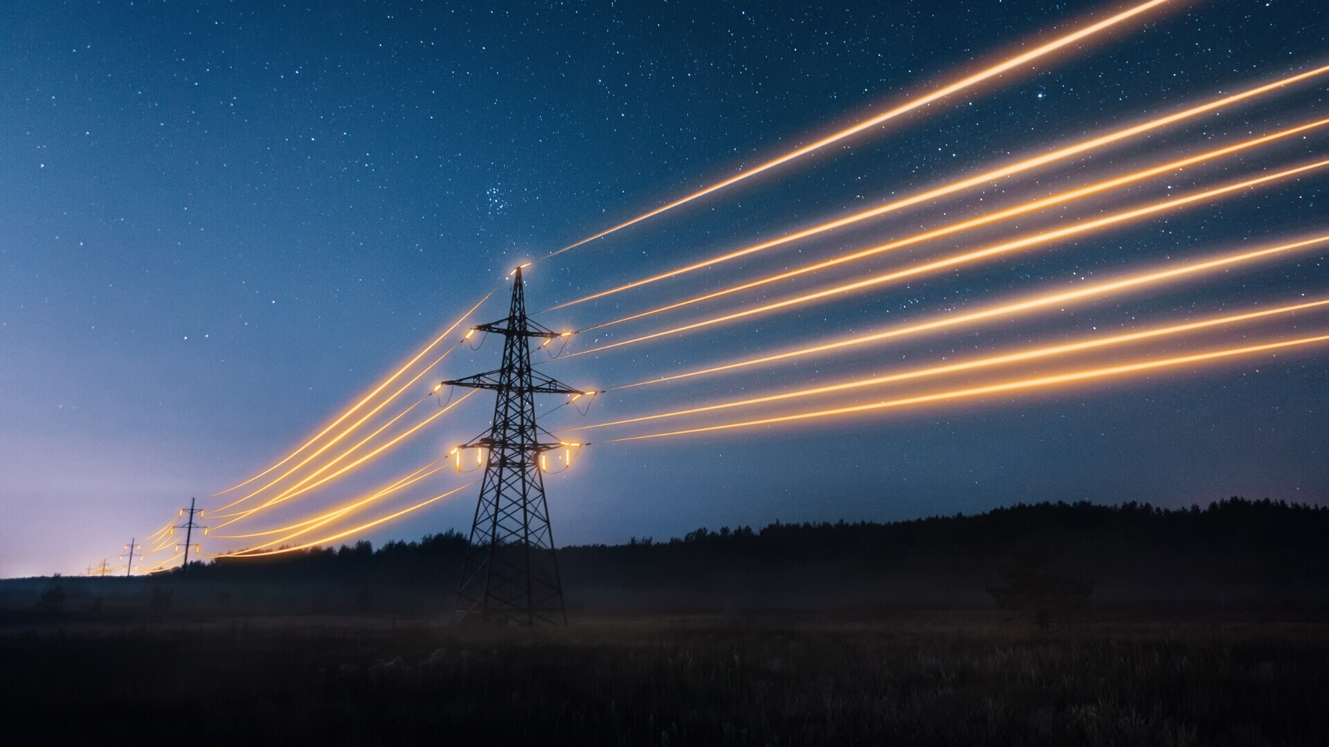 Tralicci dell’alta tensione illuminati da luci notturne su un paesaggio urbano o rurale