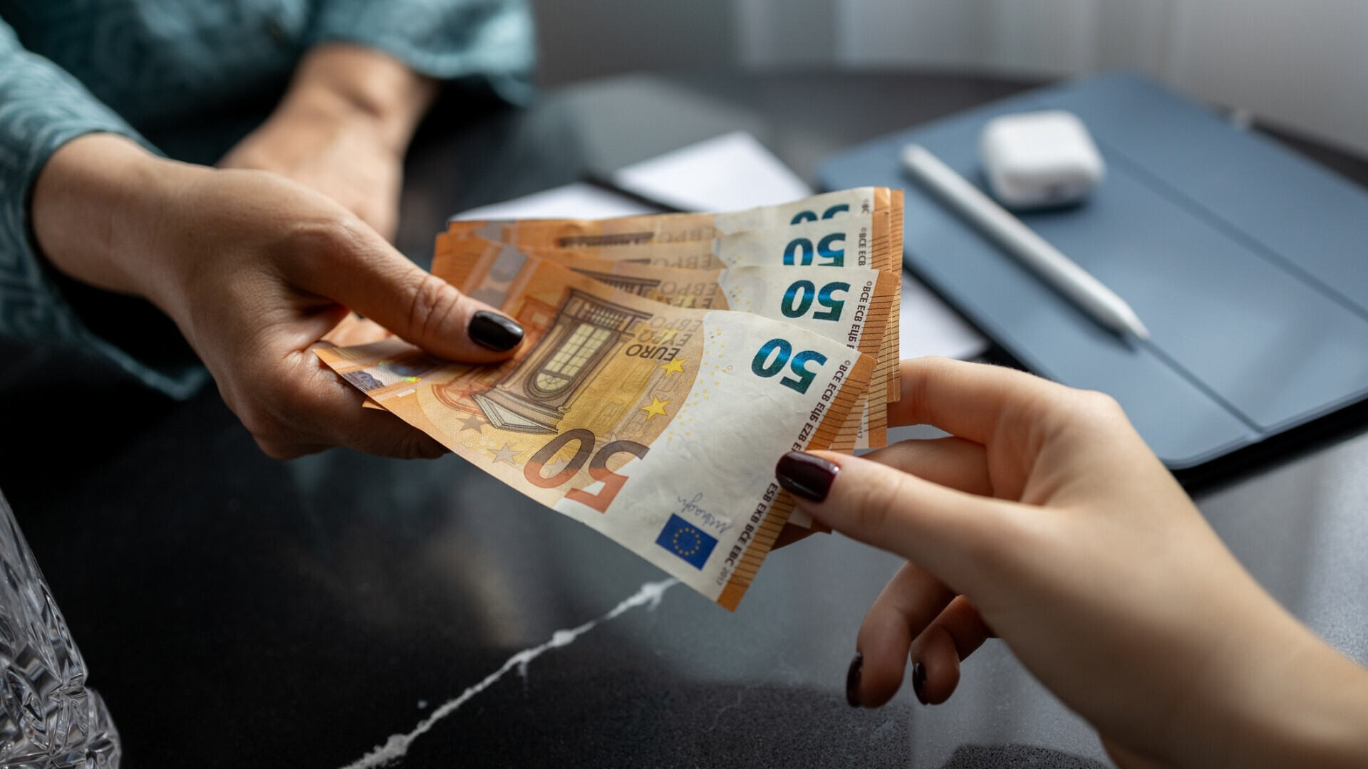 Problemi finanziari e debiti: donna che consegna banconote in euro a un’altra donna, banconota da cinquanta euro, valuta dell’Unione Europea.