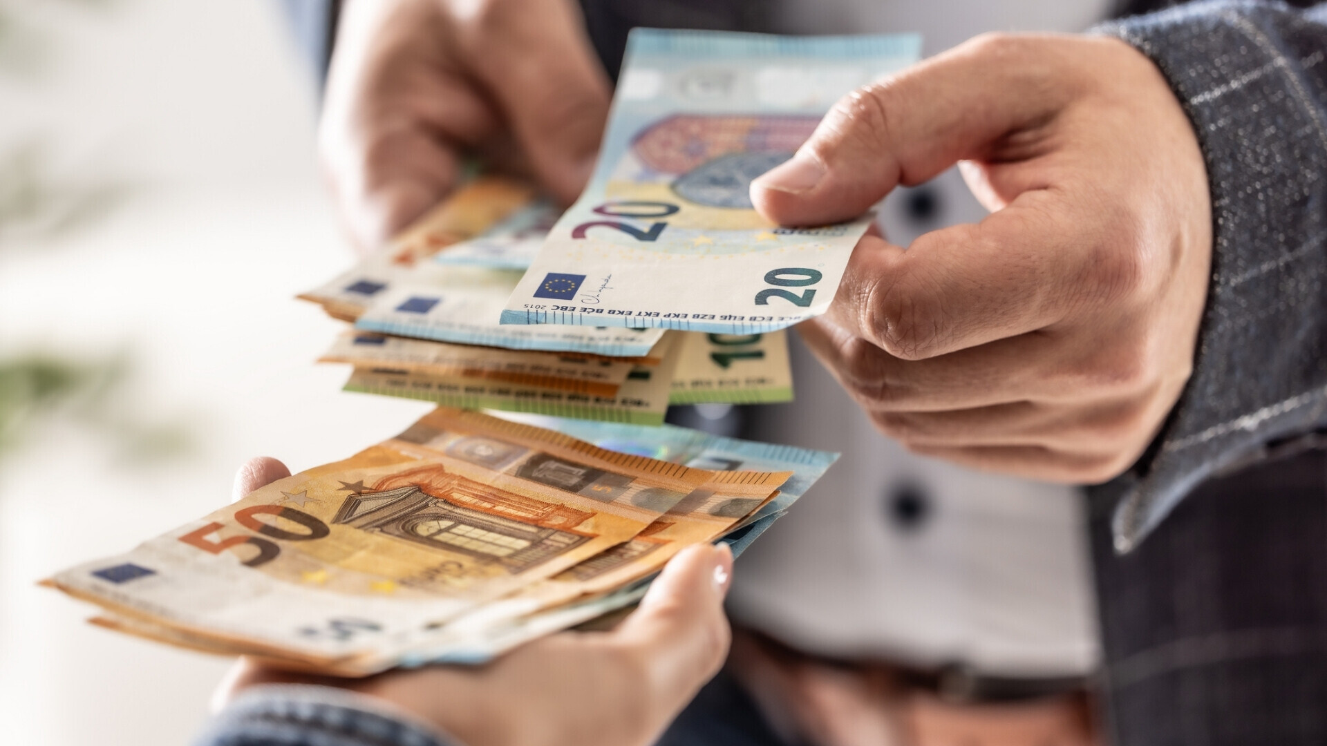 Primo piano delle mani di un uomo d’affari che scambiano banconote in euro.