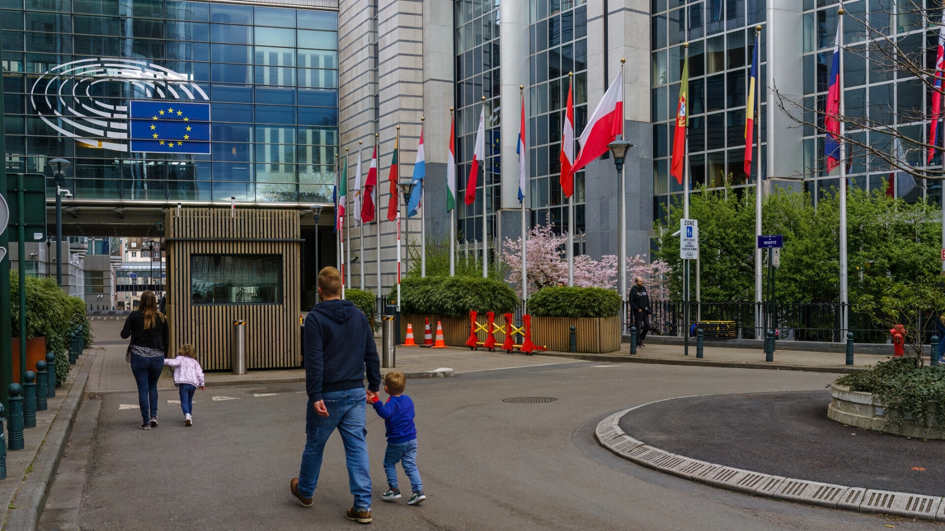 Genitori con bambini che passeggiano davanti all’edificio del Parlamento Europeo.