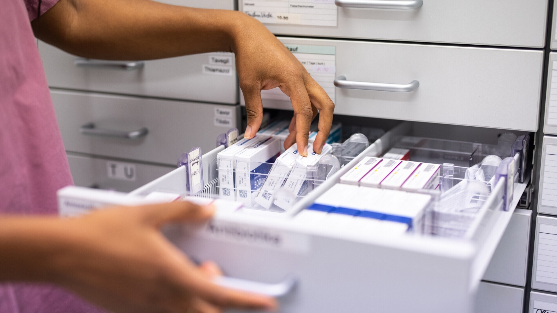 Primo piano di una farmacista che cerca medicinali su uno scaffale.