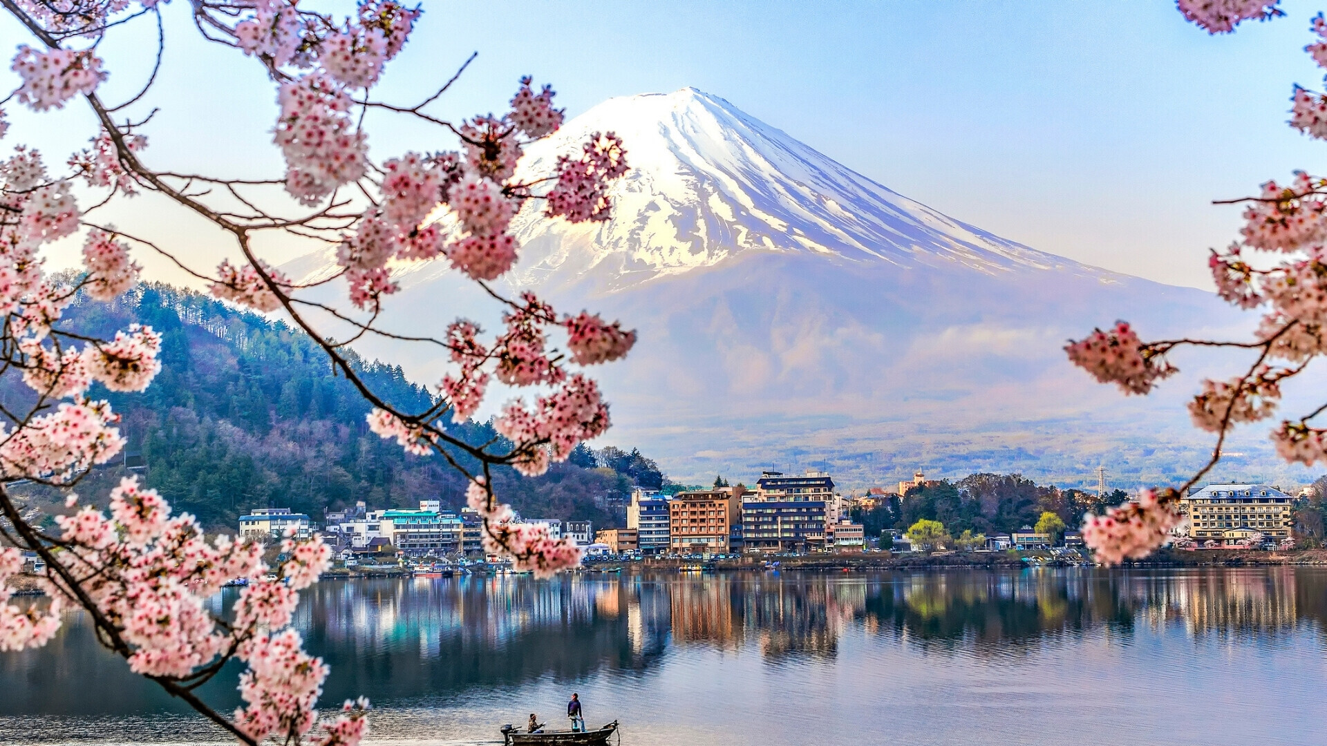 Pescatore su barca a vela nel lago Kawaguchiko con fiori di ciliegio e riflesso del Monte Fuji sullo sfondo Pescatore su una barca a vela sul lago Kawaguchiko, circondato da fiori di ciliegio in fiore e con il Monte Fuji riflesso sull’acqua calma.