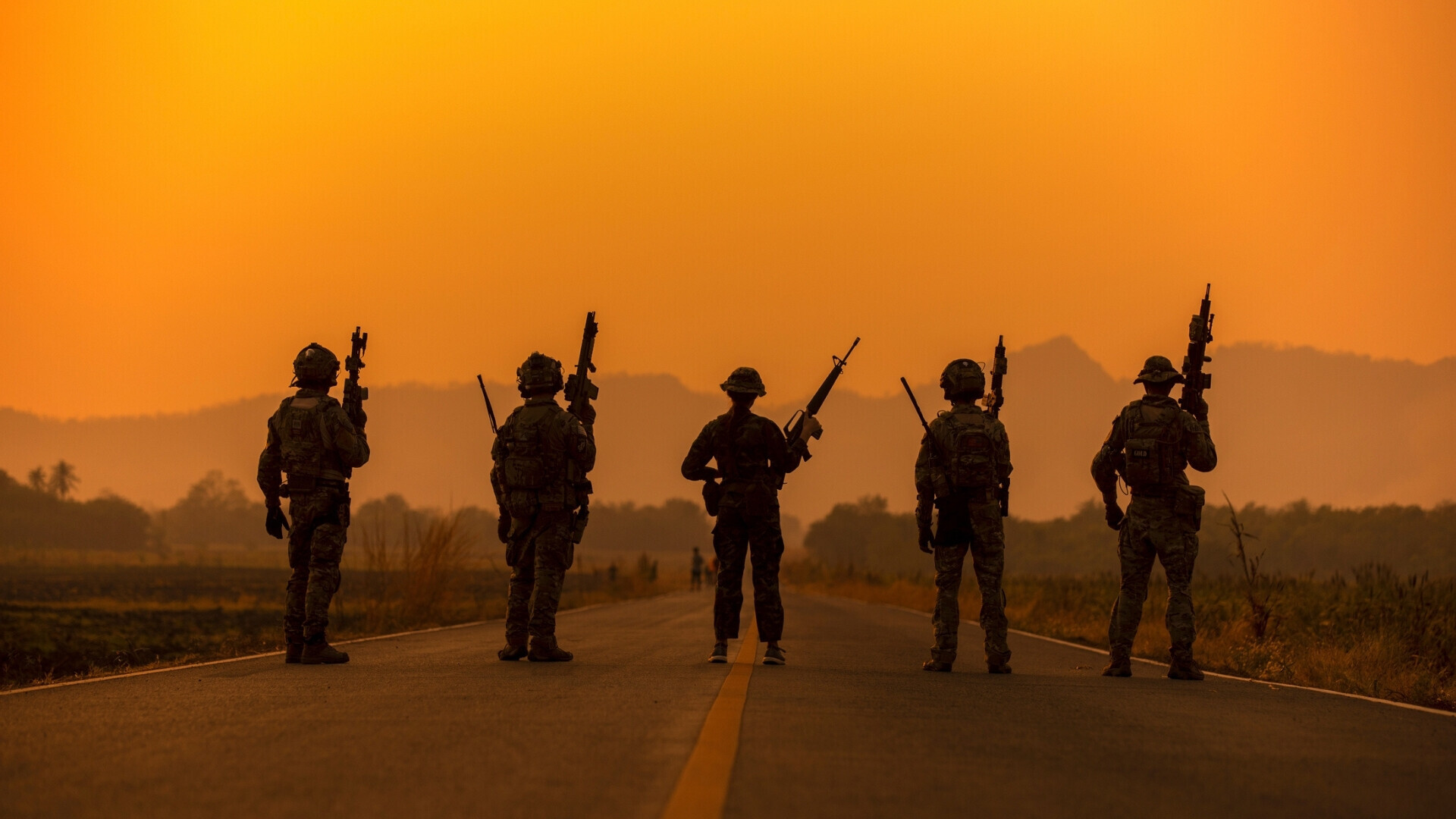 Sagome di soldati in azione sullo sfondo di un cielo arancione al tramonto, simbolo di esercito e operazioni militari.