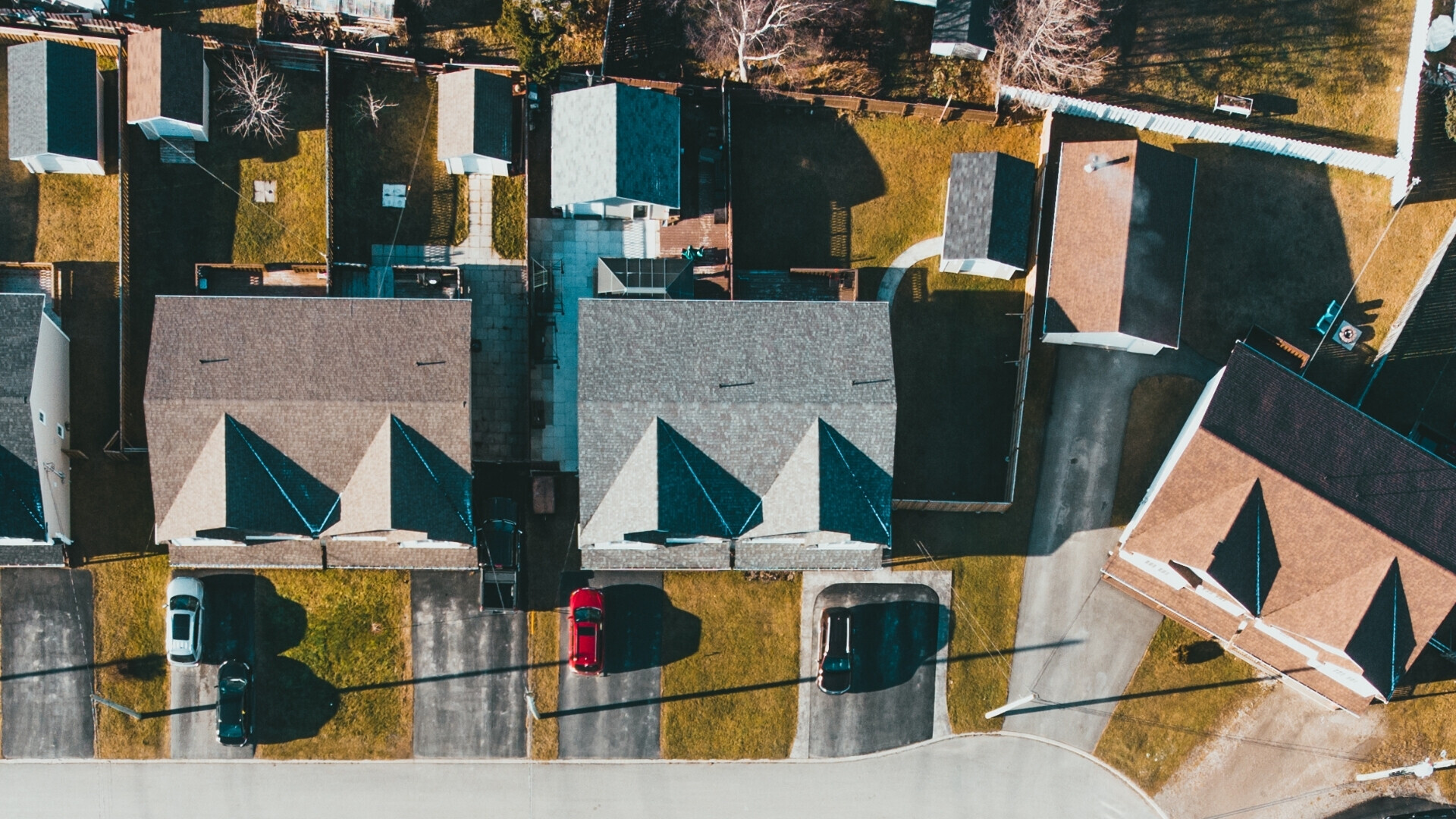 Quattro villette allineate viste dall’alto, con piccoli giardini e cortili