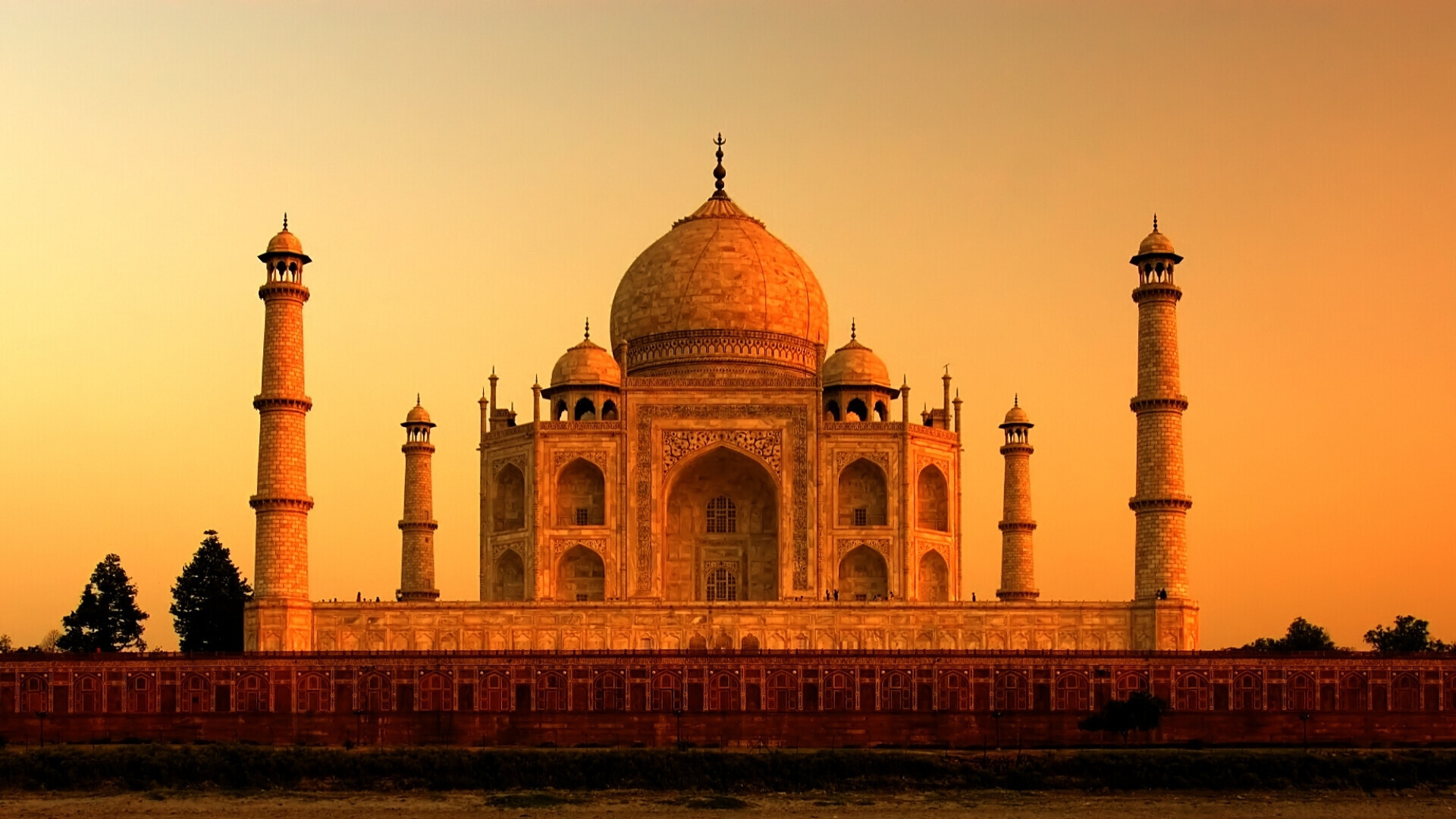 Taj Mahal visto di fronte, con il mausoleo bianco illuminato dai colori del tramonto