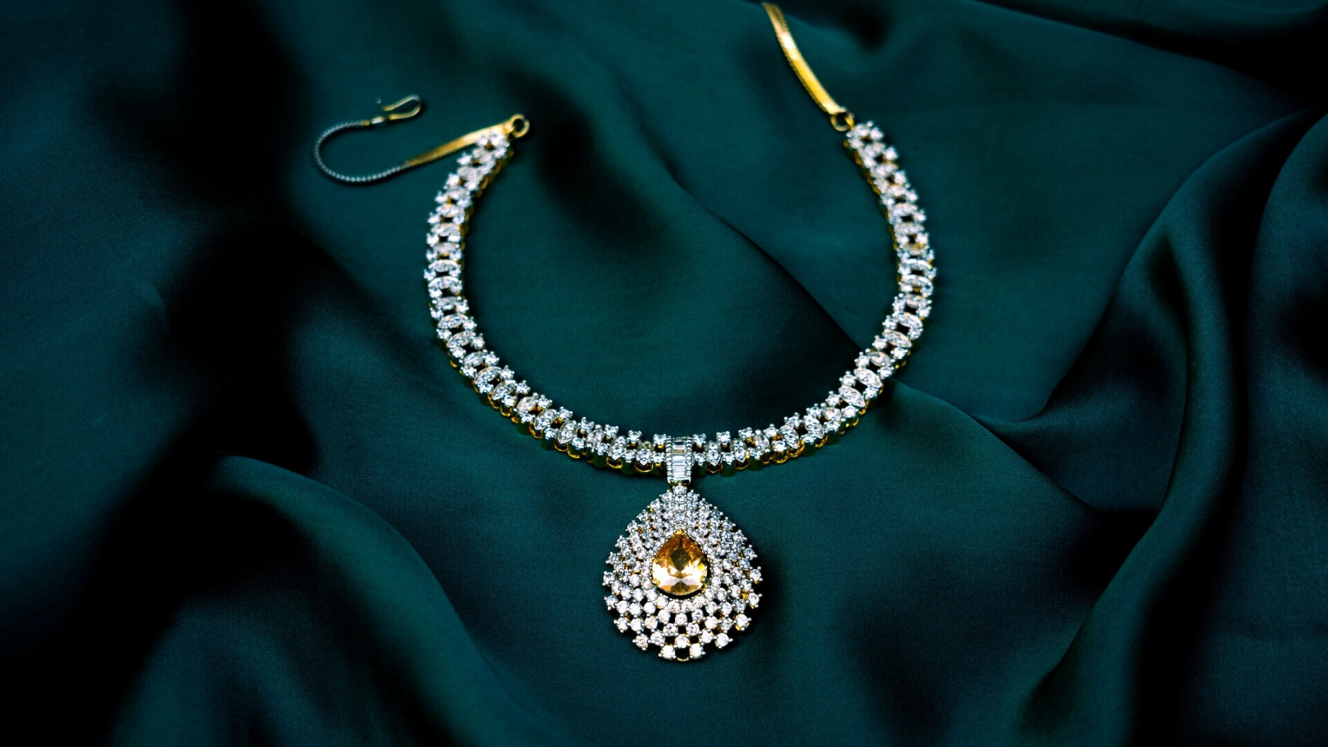 Immagine ad alta risoluzione di una lussuosa collana con gemma bianca su superficie di tessuto verde elegante, ideale per brand di moda di lusso, promozioni di gioielli o temi bridal.