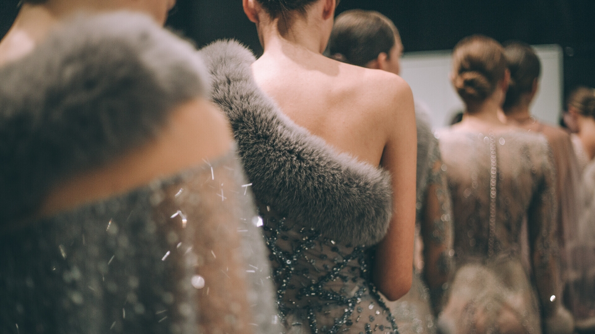 Gruppo di modelle in attesa, allineate dietro le quinte o lungo il corridoio, pronte a entrare in passerella.