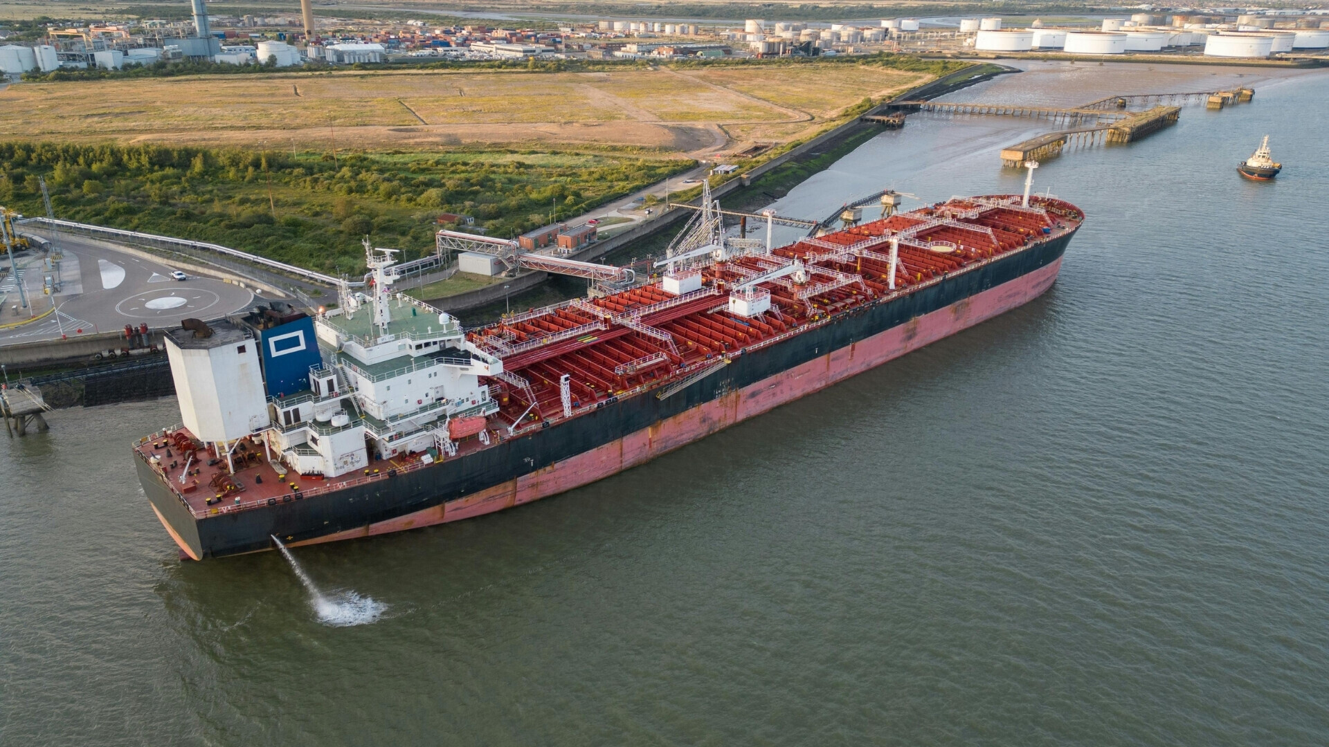 Profilo laterale di una grande nave cargo, con container impilati sul ponte e mare calmo intorno.