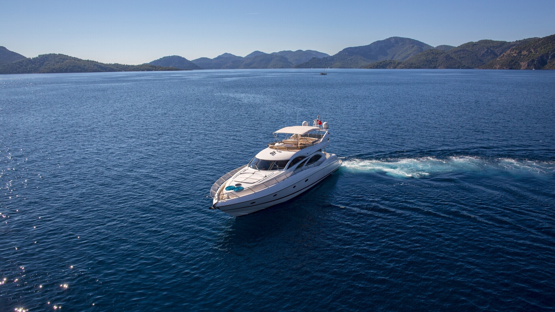Inquadratura verticale di un’imbarcazione ferma in una piccola insenatura, con il fondale marino visibile attraverso l’acqua trasparente.