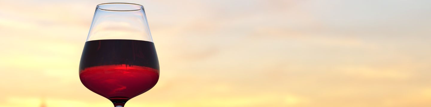 Calice di vino rosso che brilla alla luce calda del tramonto