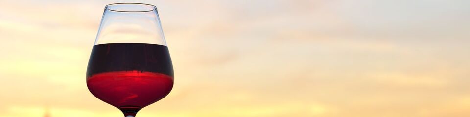Calice di vino rosso che brilla alla luce calda del tramonto