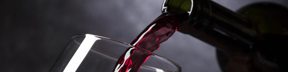 Vino_websim4 Mani esperte che versano vino rosso in un bicchiere cristallino