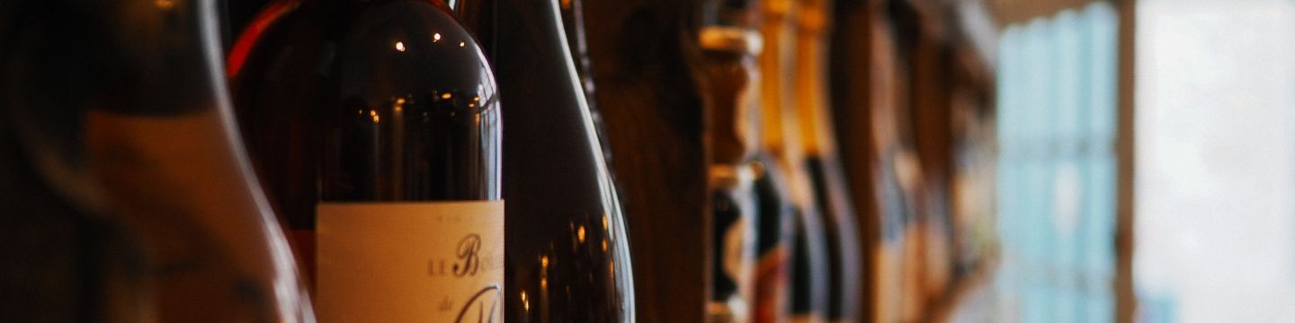 Una bottiglia di vino aperta su un tavolo rustico, circondata da calici e grappoli d'uva Una bottiglia di vino aperta su un tavolo rustico, circondata da calici e grappoli d'uva