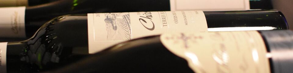 Bottiglie di vino allineate su uno scaffale di legno, pronte per la degustazione